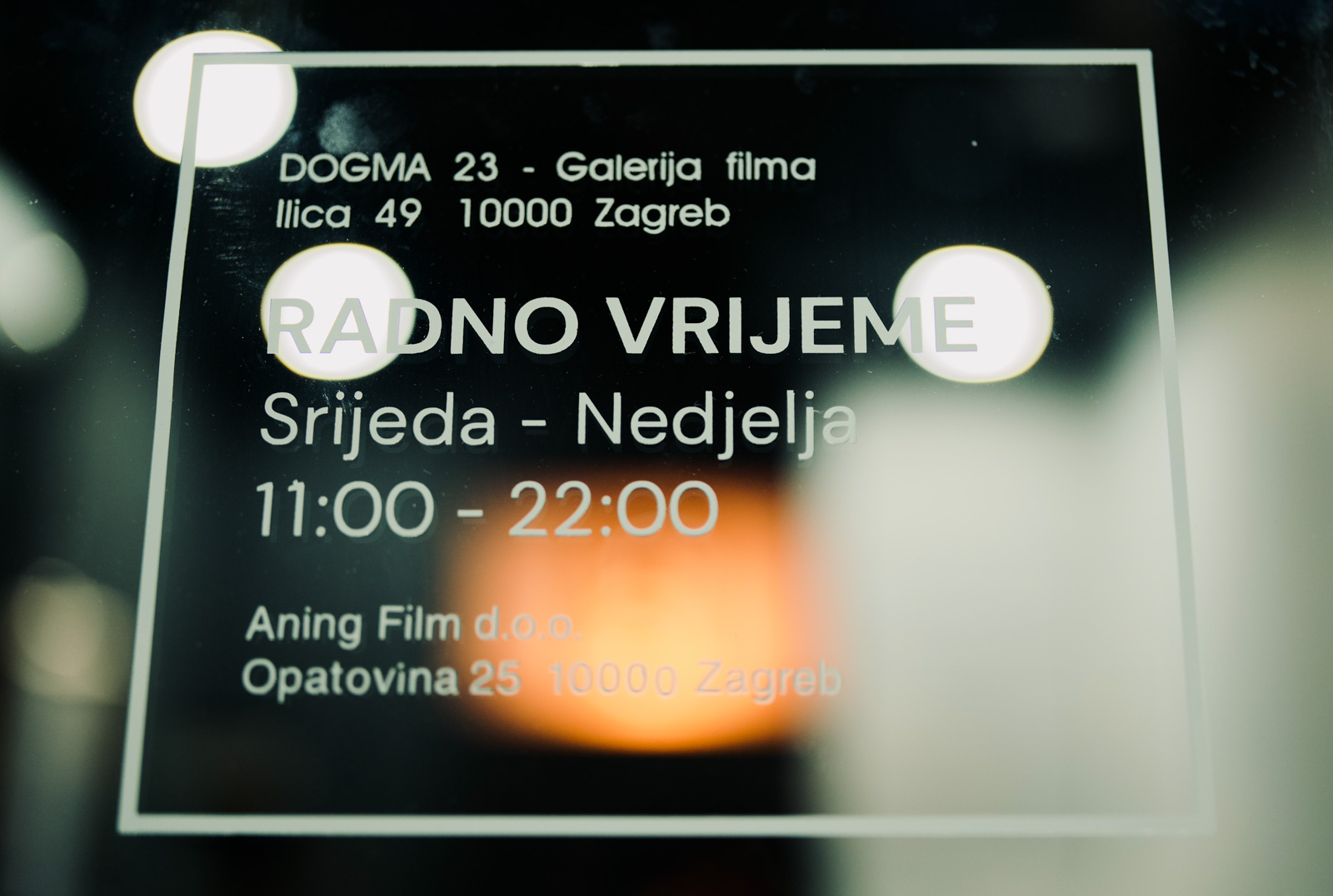 Natpis radnog vremena na staklu ulaza galerije.